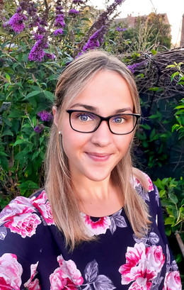 Porträt von Larissa Pliska. Frau mit Brille und mittel-langen blonden Haaren, welche zur Hälfte weggesteckt sind, lächelt in die Kamera.