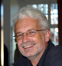 Porträt von Herrn Prof. Dr. Heinrich Tröster. Mann mit kurzen weiß-grauen Haaren, drei Tage Bart und Brille lächelt in die Kamera.