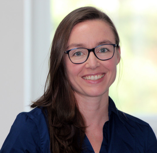 Porträt von Frau Vertr.-Prof. Dr. Vanessa Völlinger. Frau mit braunen langen Haaren und Brille lächelt in die Kamera.