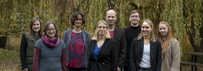 Teamfoto. Acht Personen lächeln in die Kamera.