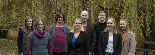 Teamfoto. Acht Personen lächeln in die Kamera.